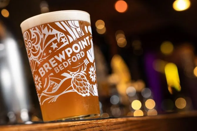 Beer sitting on a bar in focus. The beer glass is Brewpoint branded